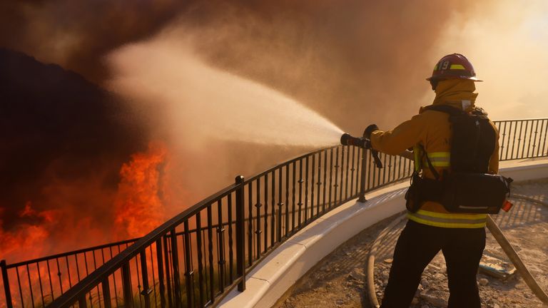 A firefighter makes a stand in front of the advancing Palisades Fire in the Pacific Palisades neighborhood of Los Angeles, Tuesday, Jan. 7, 2025. (AP Photo/Etienne Laurent)