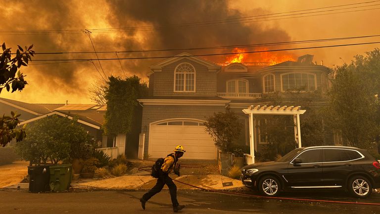 A residence burns as a firefighter battles the Palisades Fire in the Pacific Palisades neighborhood of Los Angeles Tuesday, Jan. 7, 2025. (AP Photo/Eugene Garcia)