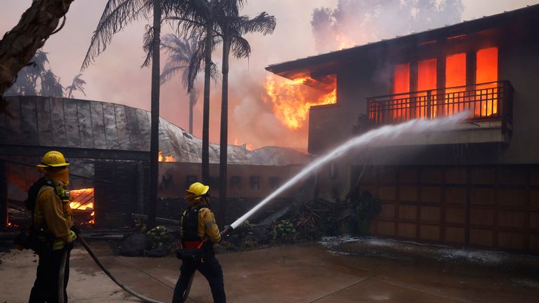 Firefighters hose down flames as the Palisades Fire destroys a residence in the Pacific Palisades neighborhood of Los Angeles, Tuesday, Jan. 7, 2025. (AP Photo/Etienne Laurent)