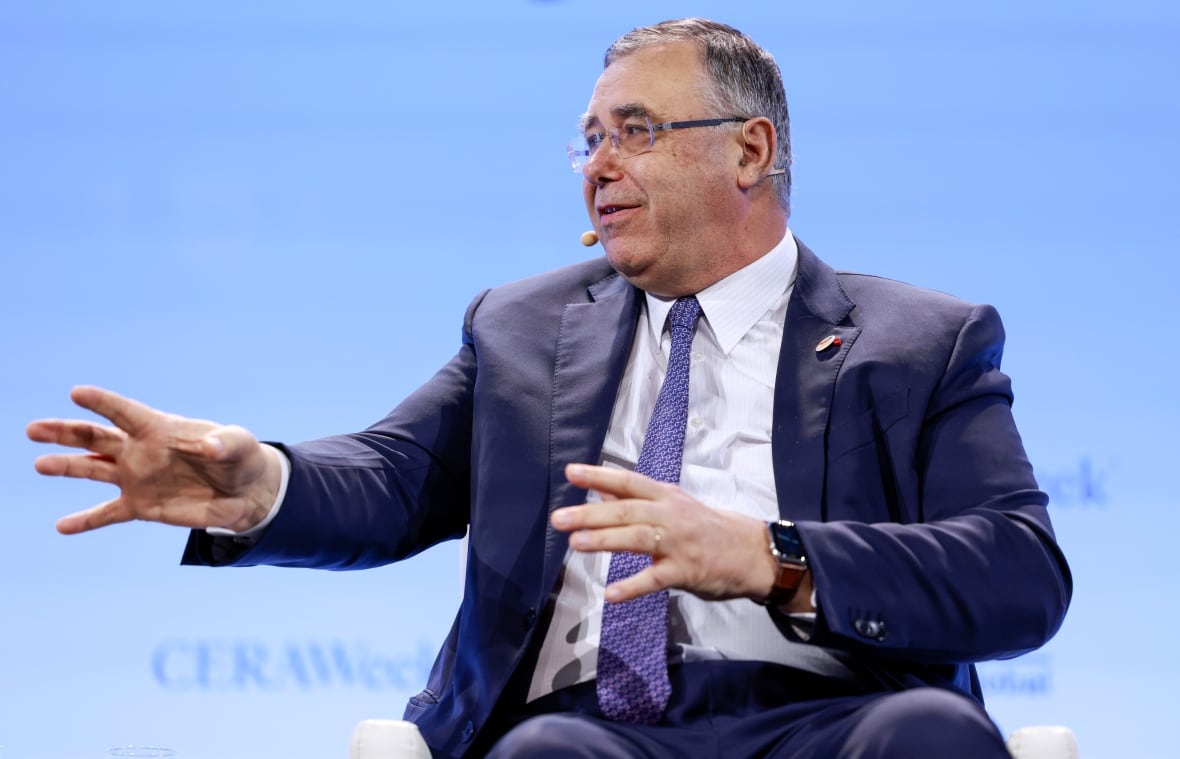 A man wearing a blue suit with a French flag pin makes an energetic gesture while speaking during a panel at CERA Week, a major energy conference.